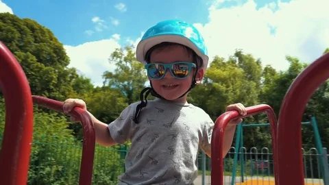 Little Boy spinning on the carousel with helmet on the head Stock Footage 79976332
