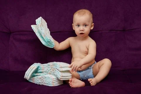Little boy with stack of diapers or nappies on purple background Stock Photos