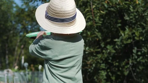 Little boy in a straw hat and sunglasses walking and playing in the garden Stock Footage 280339833