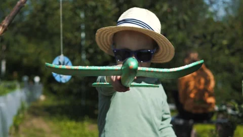 Little boy in a straw hat and sunglasses plays with an airplane Stock Footage 280339872