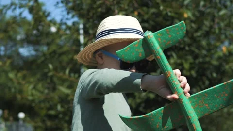 Little boy in a straw hat and sunglasses plays with an airplane Stock Footage 280339874