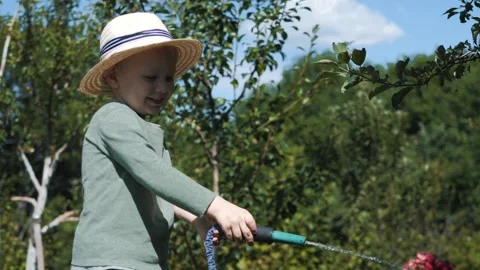Little boy in a straw hat and sunglasses walking and playing in the garden Stock Footage 280340093