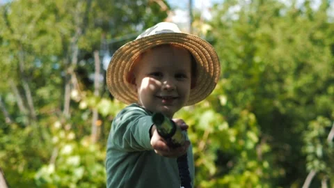 Little boy in a straw hat and sunglasses walking and playing in the garden Stock Footage 280340104