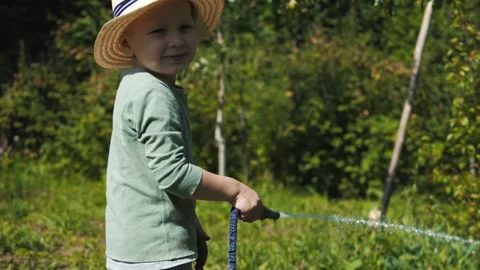Little boy in a straw hat and sunglasses walking and playing in the garden Stock Footage 280340138