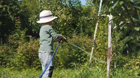 Little boy in a straw hat and sunglasses walking and playing in the garden Stock Footage 280340143