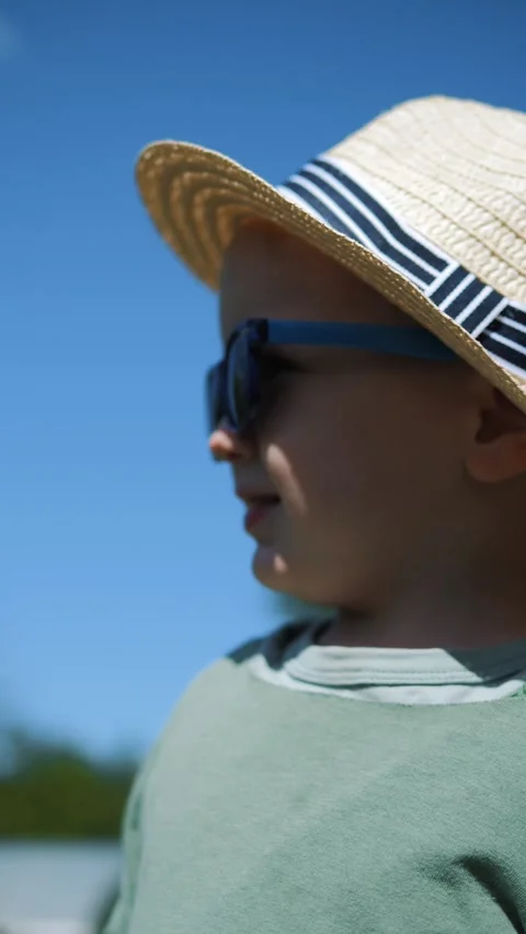 Little boy in a straw hat and sunglasses walking and playing in the garden Stock Footage 280340166
