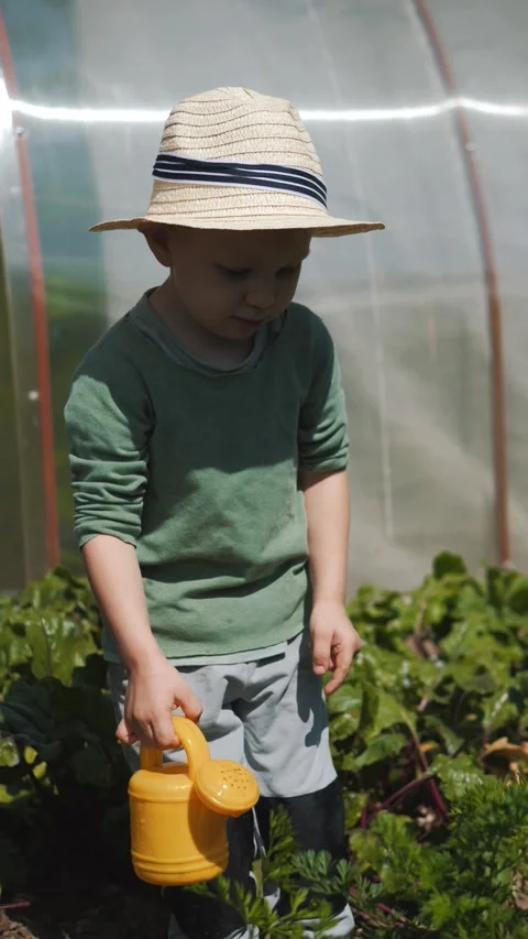 Little boy in a straw hat and sunglasses walking and playing in the garden Stock Footage 280340175