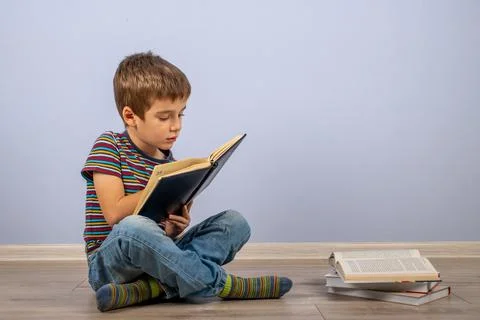 A little boy, studying behind a stack of books and looking at a diary. A male Stock Photos