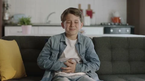 Little boy suffering from stomachache while sitting on sofa at home. Stock Footage 190518791