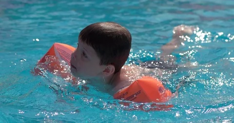 A little boy is swimming in the pool with rad sleeves Stock Footage 80722053