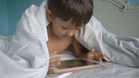 Little boy with tablet computer on the bed under the blanket Stock Footage 80840703