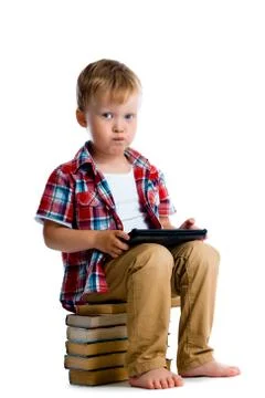Little boy with a tablet computer sitting on the books Stock Photos