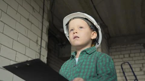 A little boy with a tablet with documents is standing on a construction site Stock Photos