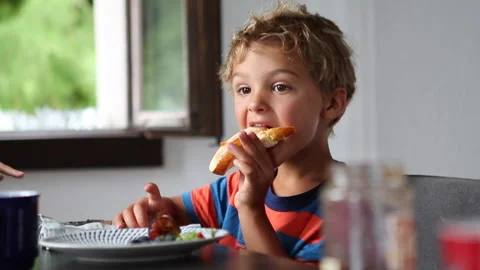 Little boy taking a bite of bread with jelly in morning breakfast table Stock Footage 138131059