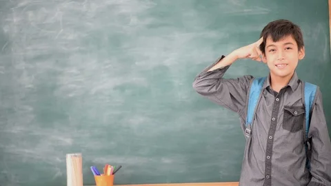Little boy thinking in front of blackboard in the class room Stockbeeldmateriaal 105207984