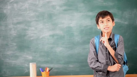 Little boy thinking in front of blackboard in the class room Stockbeeldmateriaal 105207991