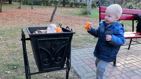 A little boy throws garbage in the trash in the street. The concept of waste man Stock Footage 97720896