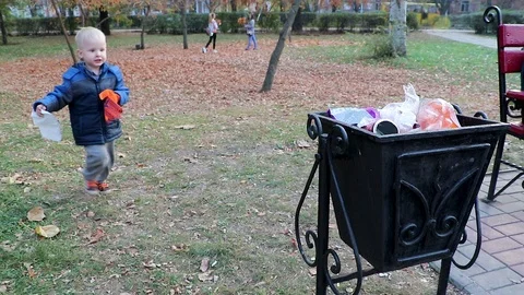 A little boy throws garbage in the trash in the street. The concept of waste man Stock Footage 97720950