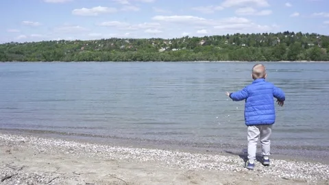 Little boy throws pebbles into the water on the banks of the Danube. Stock Footage 152016406