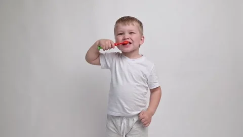 Little boy with a toothbrush on a white background carefully brushes his teeth Stock Footage 244346996