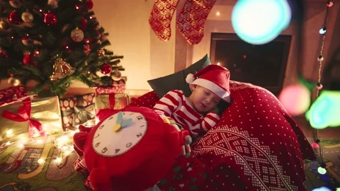 Little boy with toy clock fell asleep while waiting for Santa Claus near Stock Footage 73004255
