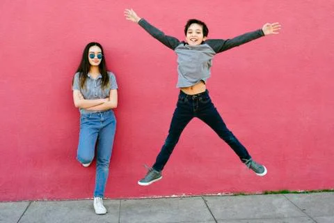 A little boy tries to impress his older sister by jumping high.  She stands a Stock Photos