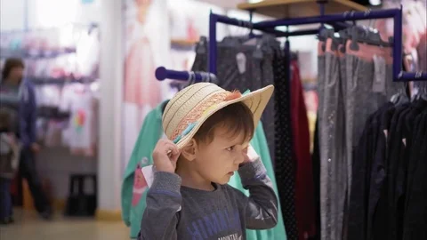 A little boy trying on a hat in a store and rejoicing Stock Footage 82077698