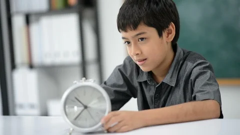 Little boy turning round clock in the classroom Stockbeeldmateriaal 105273139