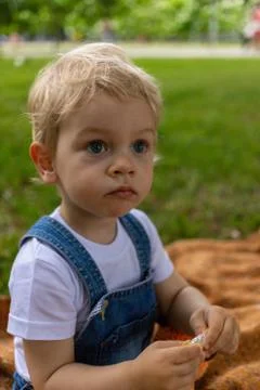A little boy of two years in a blue jumpsuit and a white T-shirt walks in the 스톡 사진