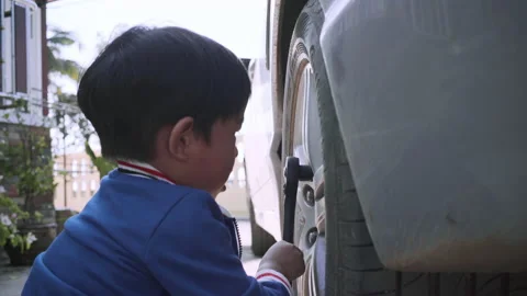 Little boy use wrench tool fix car tire Stock Footage 145682990