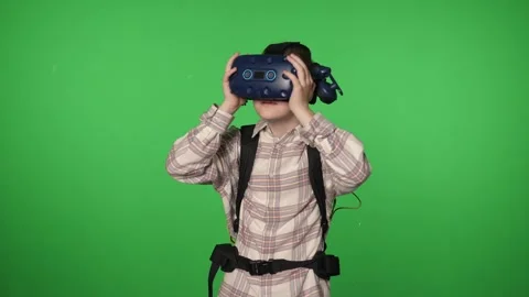 A little boy uses a virtual reality headset in a studio with a green background. Stock Footage 316593080