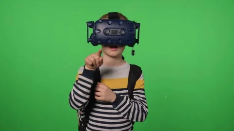 A little boy uses a virtual reality headset in a studio with a green background. Stock Footage 317000647