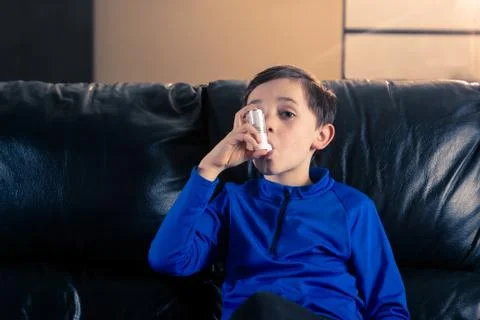 Little boy using an asthma inhaler indoors Stock Photos