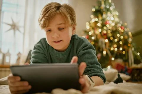 Little Boy Using Digital Tablet near Christmas Tree at Home Stock Photos