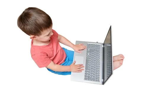 Little boy using laptop while sitting on floor. Child typing on computer to l 库存照片