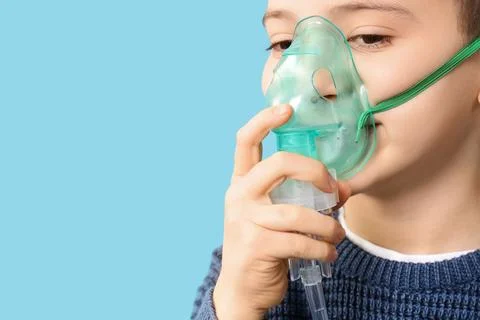 Little boy using nebulizer on blue background, closeup Stock Photos