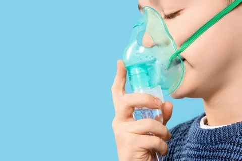 Little boy using nebulizer on blue background, closeup Stock Photos