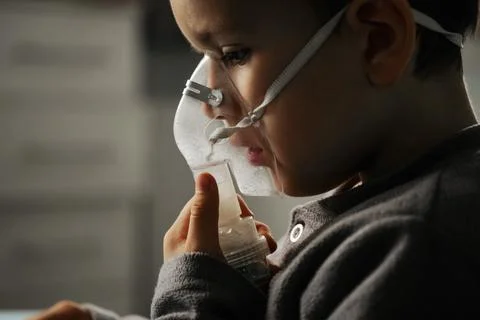 Little boy using nebulizer during inhaling therapy at home Stock Photos