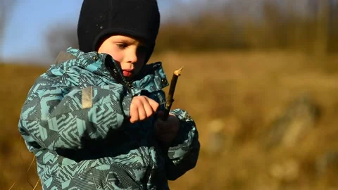 Little boy using a real sharp knife to sharpen a wooden stick. Raising children. Stock Footage 170997186