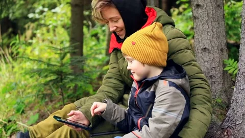 Little boy using smart phone with mother outdoor in mountains forest camp. Trave 스톡 동영상 215842329