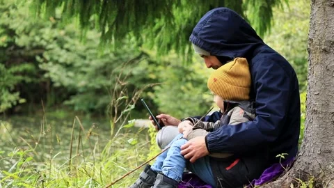 Little boy using smart phone with father outdoor in mountains forest camp. Trave 스톡 동영상 215842489