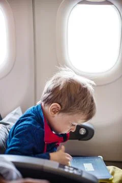 Little boy using tablet on board of aircraft Stock Photos