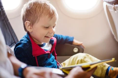 Little boy using tablet on board of aircraft Stock Photos
