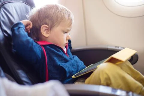 Little boy using tablet on board of aircraft Stock Photos