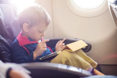 Little boy using tablet on board of aircraft Stock Photos