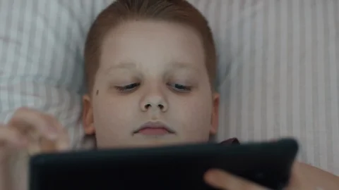 Little Boy Using Tablet Computer Lying In Bed Stock Footage 103353617