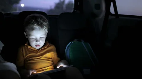 Little boy using tablet pc during car travel at night Stock Footage 46319788