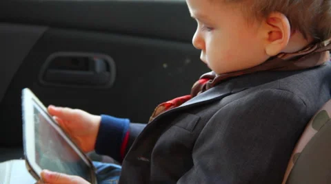 Little boy using a tablet sitting in a car seat car Stock Footage 63138355