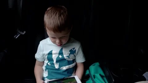 Little Boy Using a Tablet Sitting in a Car Seat Car Stock Footage 66557400