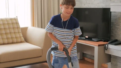 A little boy vacuums and dances. A boy is cleaning the house. Stock Footage